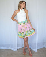 Woman wearing a white cotton-blend Veronica twist top paired with a pink lemon-print skirt.