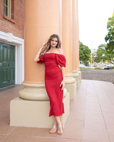 Woman wearing a red stretch crepe midi dress with puff sleeves and a ruched front, styled off-the-shoulder.