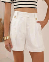 Tailored white linen-blend Victoria shorts featuring a high-waisted design, pleated front, and gold button accents.