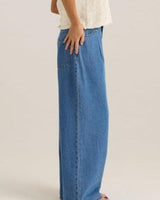 Side view of Yara wide-leg blue denim jeans featuring front pleats, functional pockets, and a relaxed fit.