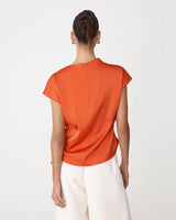 Back view of a burnt orange pleated draped top with cap sleeves and an invisible back zipper closure.