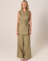 Olive green sleeveless wrap vest with a notched lapel and self-tie waist belt, paired with matching wide-leg trousers.