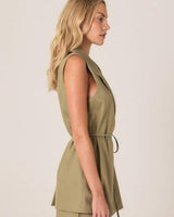 Olive green sleeveless wrap vest with a notched lapel and self-tie waist belt in a tailored cotton-blend fabric.